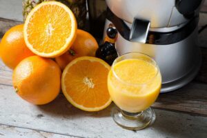 Bedste slow juicer med friske appelsiner, nogle hele og nogle halverede, som ligger på et rustikt træbord